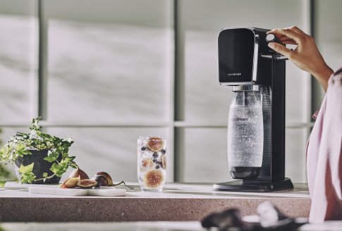 Kobieta gazuje wodę w czarnym saturatorze do wody SodaStream Art. 