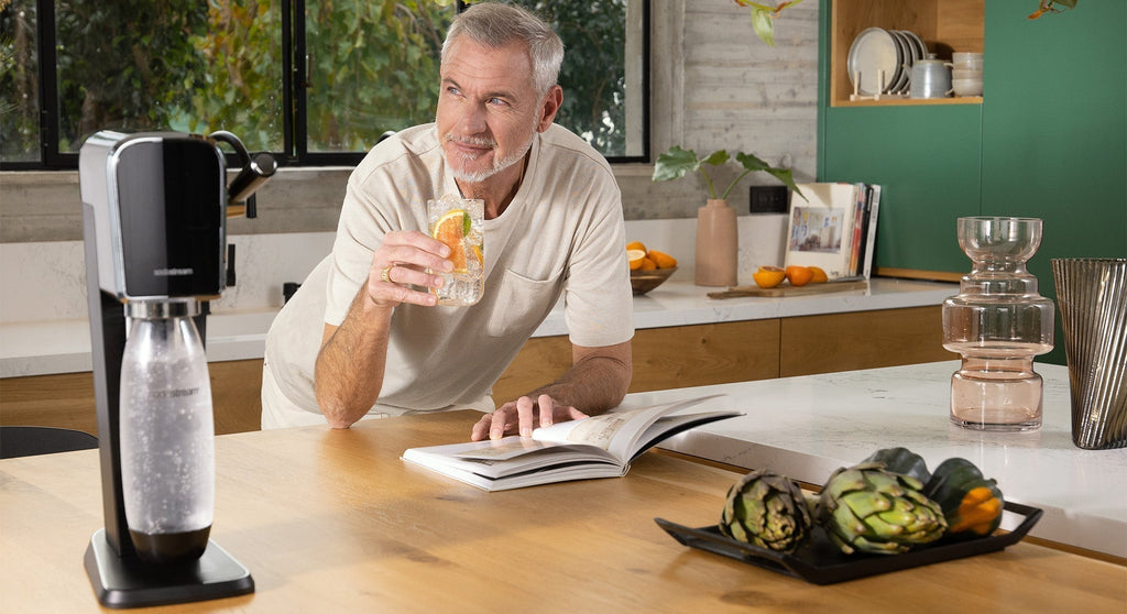 Starszy mężczyzna pije wodę gazowaną z saturatora SodaStream Art