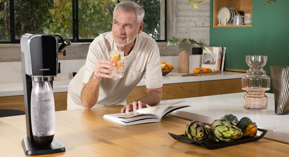 Starszy mężczyzna pije wodę gazowaną z saturatora SodaStream Art