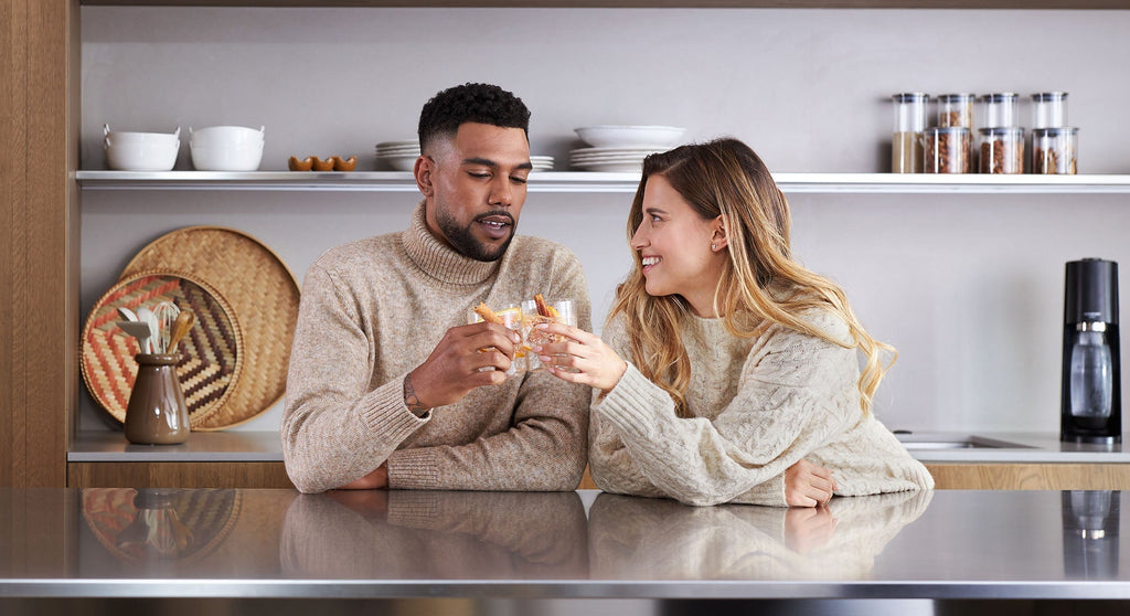 Para siedząca przy blacie kuchennym i pijący wodę gazowaną