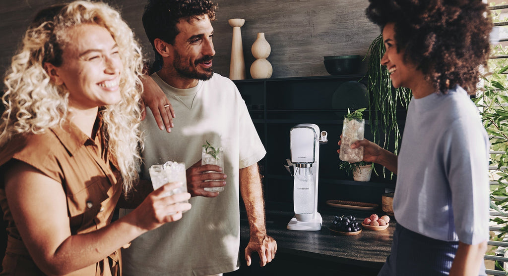 Trójka ludzi rozmawiających i popijających wodę z lodem z saturatora