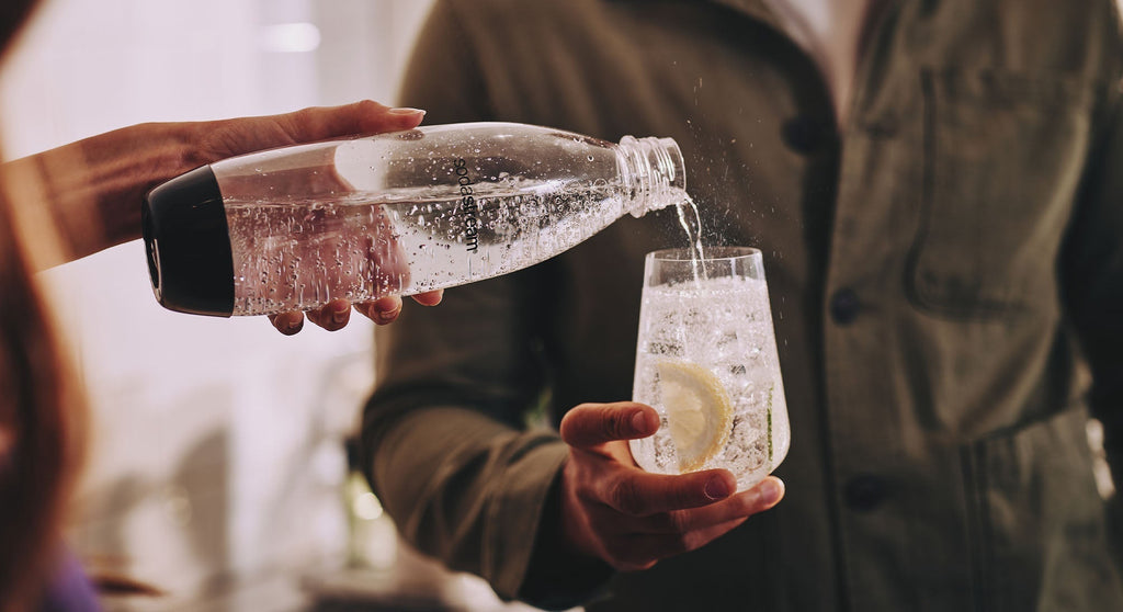 Osoba nalewająca mężczyźnie do szklanki wodę gazowaną SodaStream